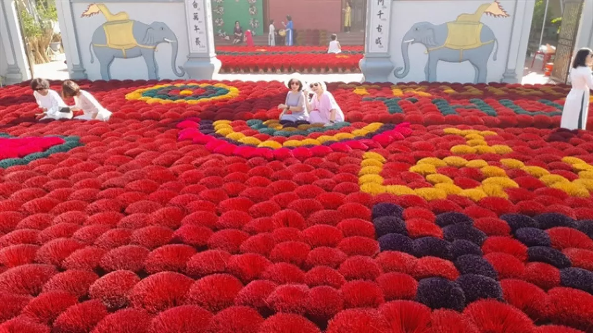 Visitors pose for photos among colourful incense stick "bouquets" in Quảng Phú Cầu Village.